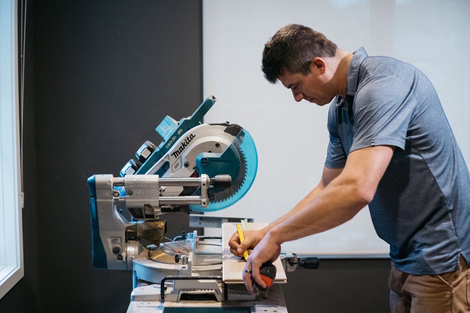 A flooring craftsperson working at a miter saw