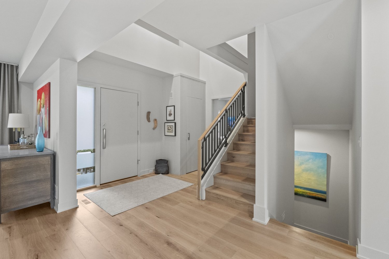 Light wood flooring in an entryway beside a staircase